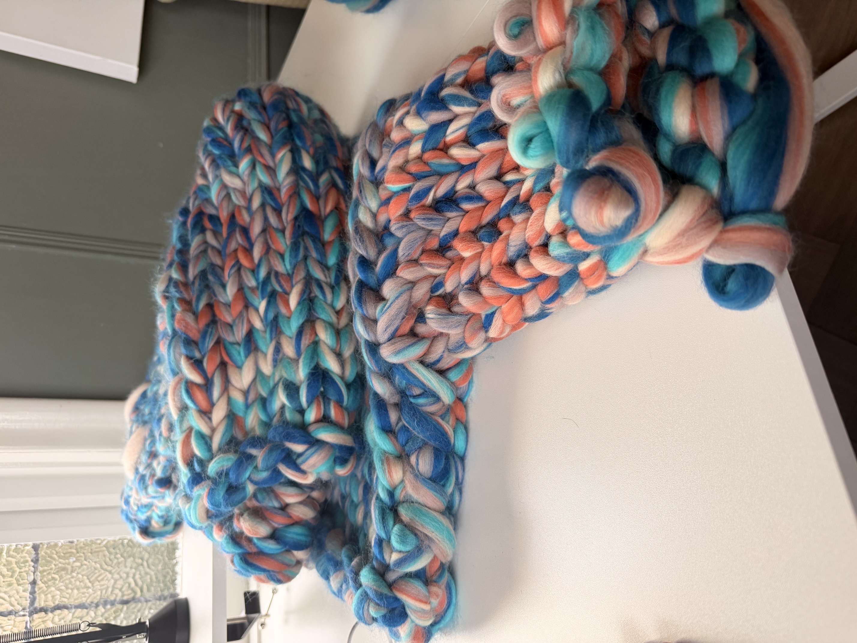 Soft chunky wool roving and oversized wooden knitting needles laid out ready to begin.
