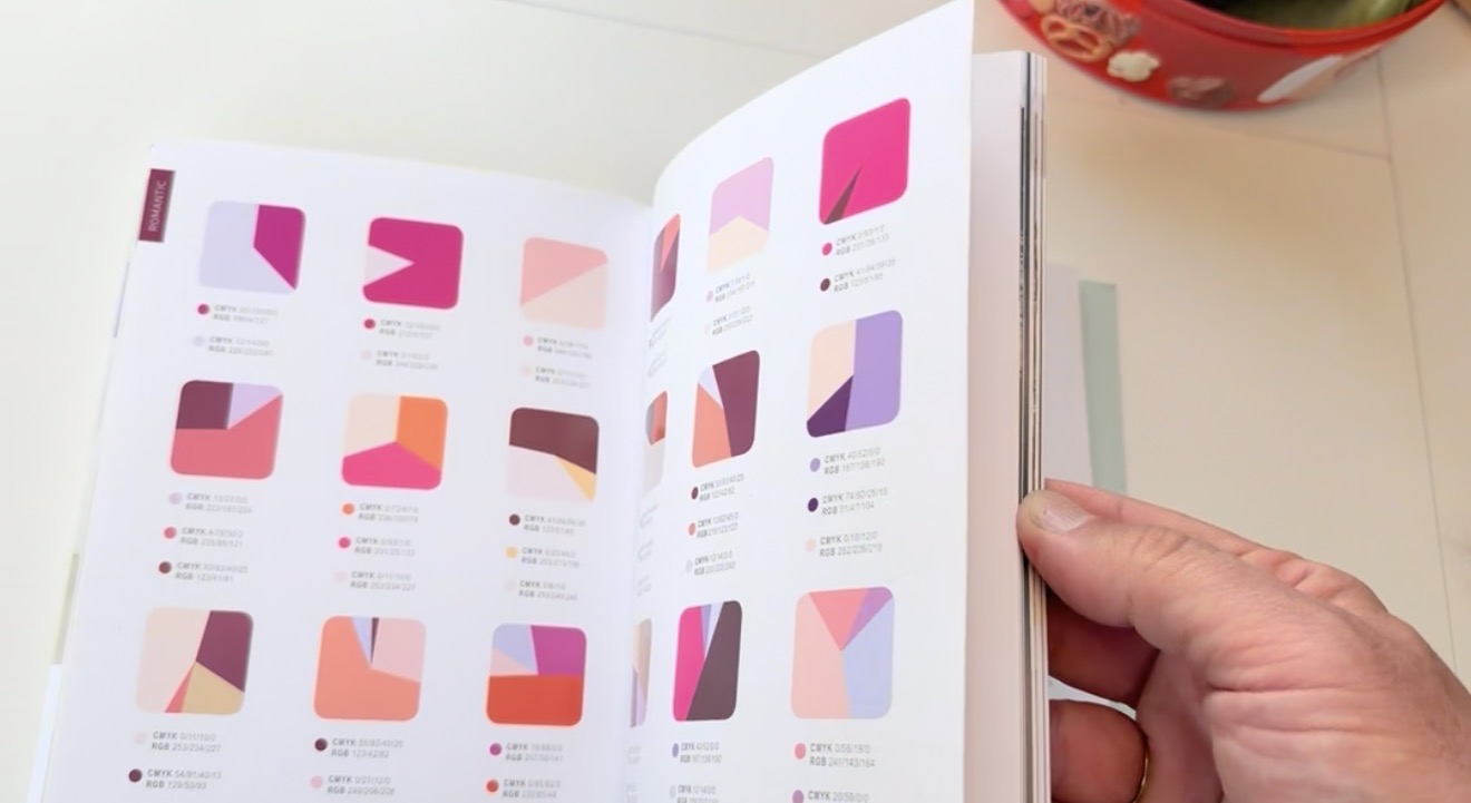 An open colour-reference book showing romantic pink and coral palettes with CMYK and RGB values, part of next season's research.