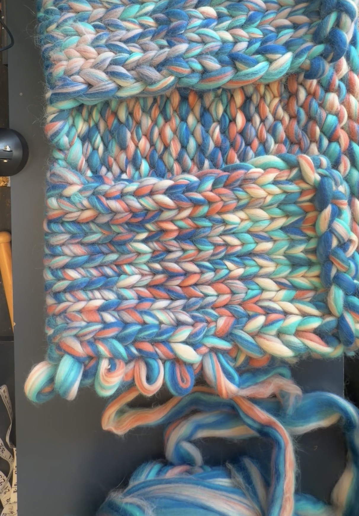 A pair of hands knitting chunky wool on big needles