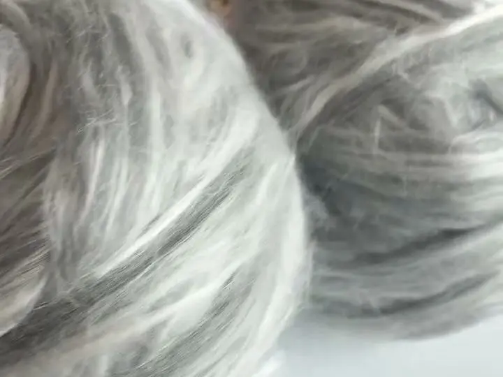 An extreme close-up of very fine silver merino-silk fibres lifting apart from the strand.