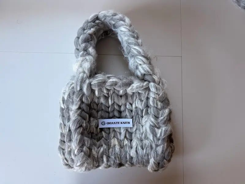 The finished silver-grey merino-silk chunky mini bag with its white Gigante Knits label.