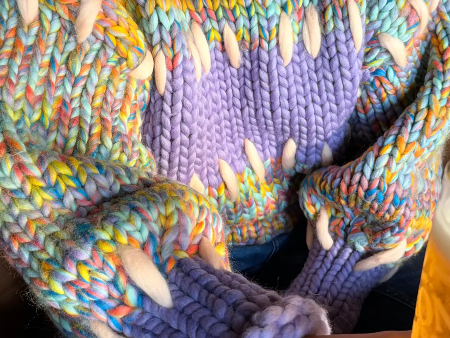 Nærbillede af Gigante-sweateren: Pastel Rainbow-masker, Lavender-båndet over brystet og forstingene i Eggshell.