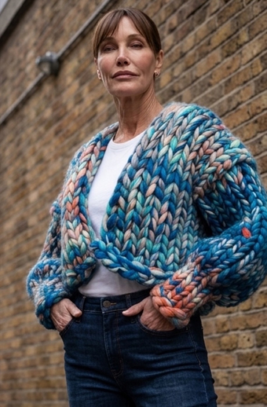 En færdig grovstrikket håndstrikket cardigan i bløde havblå farver, båret udendørs.