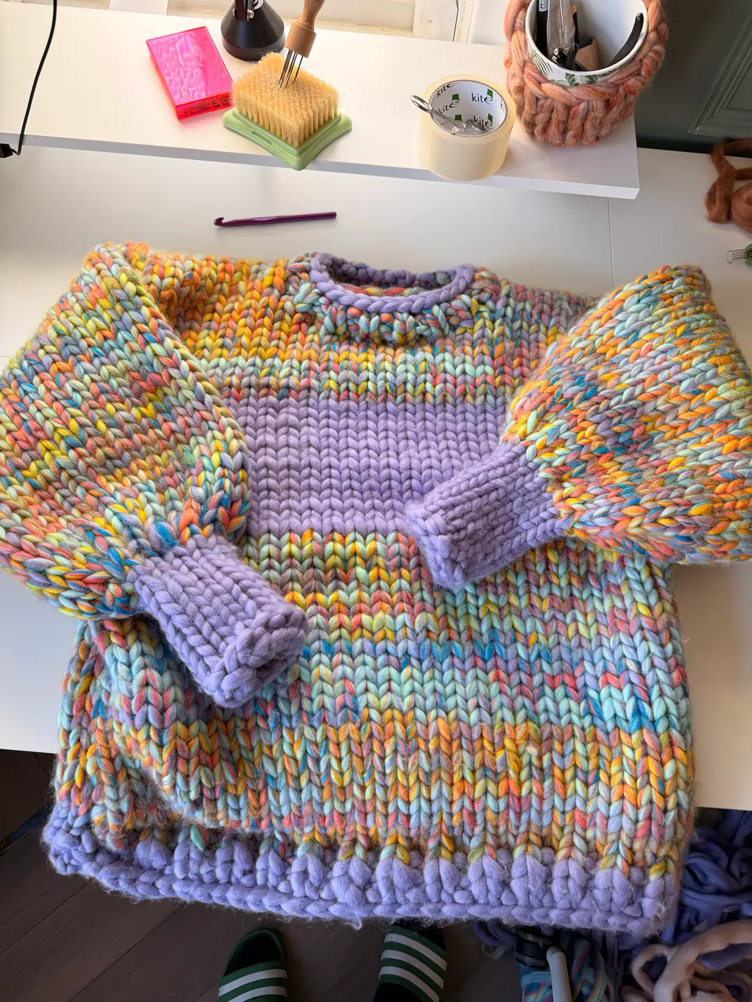 Den færdige sweater lagt fladt på studiebordet før forstingene: Lavender-båndet, manchetterne og kanten, men endnu ingen Eggshell-sting.
