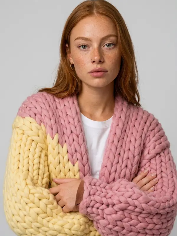 The Dual cardigan worn with arms folded, yellow sleeve and pink sleeve.