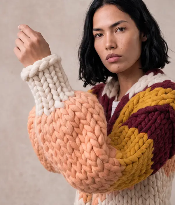 The Film Roll cardigan with one arm raised, the peach and cream sleeve filling the frame.