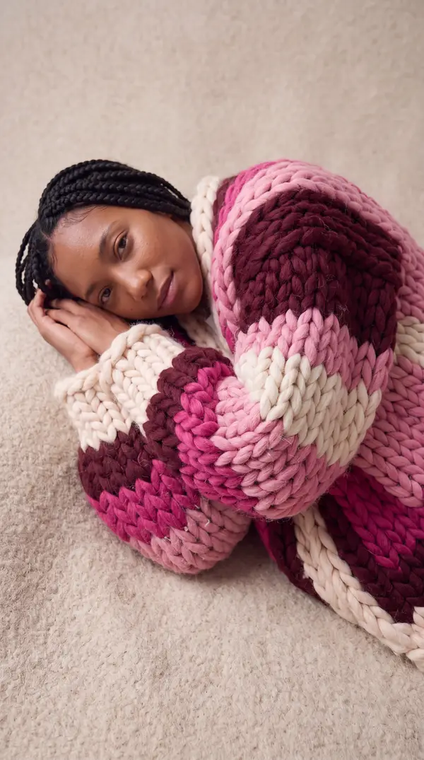 A close view of the Retro Neon cardigan, wine, pink and cream stitches curled around the wearer.